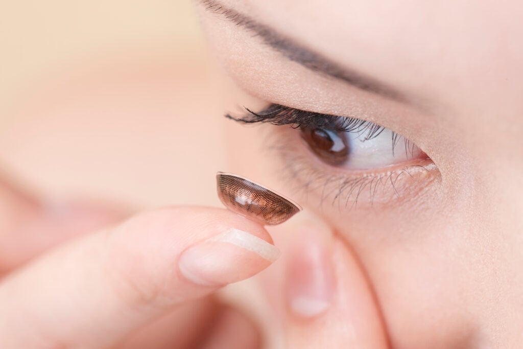 Close up shot of woman tries to fit color contact lenses