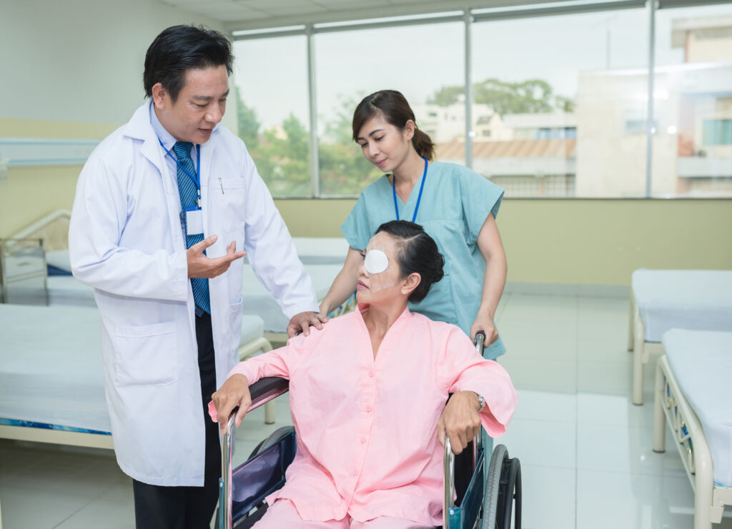 Female patient being transported through a wheelchair talks to a doctor after her cataract operation