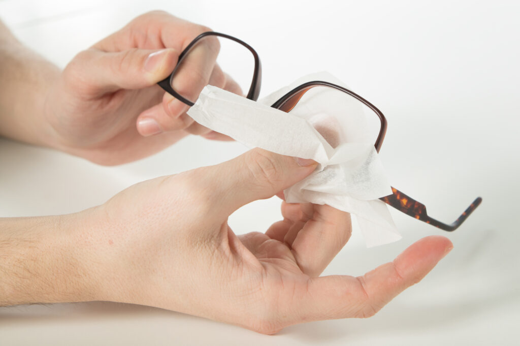 Focused shot on cleaning eye glasses using tissue paper