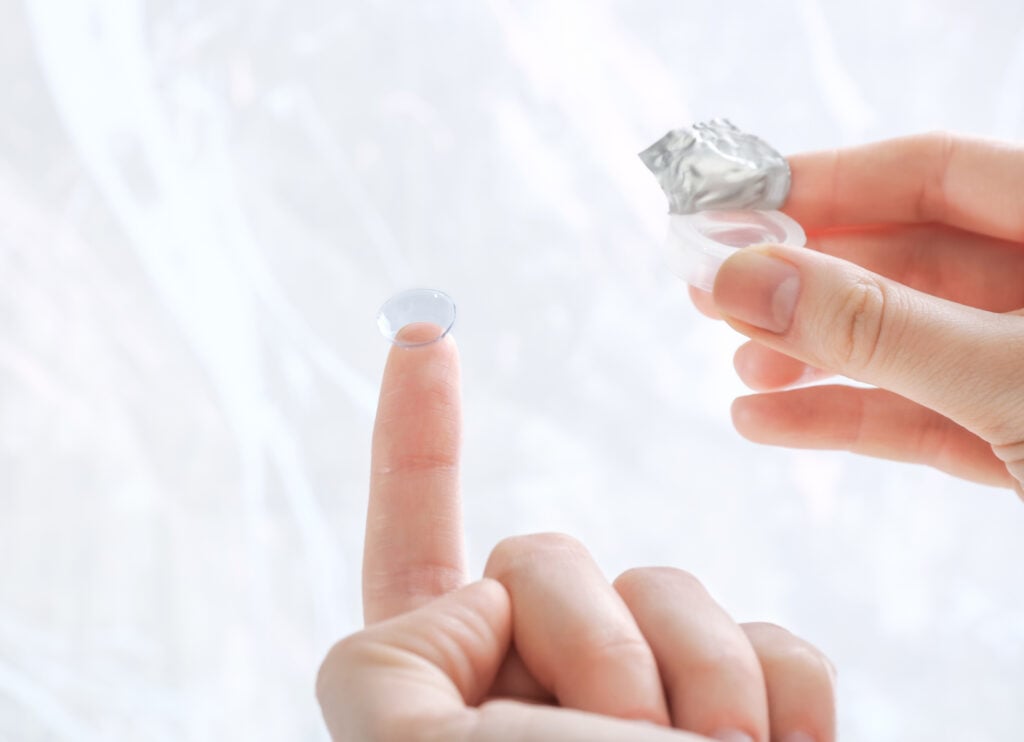 Gas permeable contact lenses being held by woman outside of photo