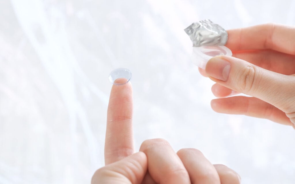 Gas permeable contact lenses being held by woman outside of photo edited