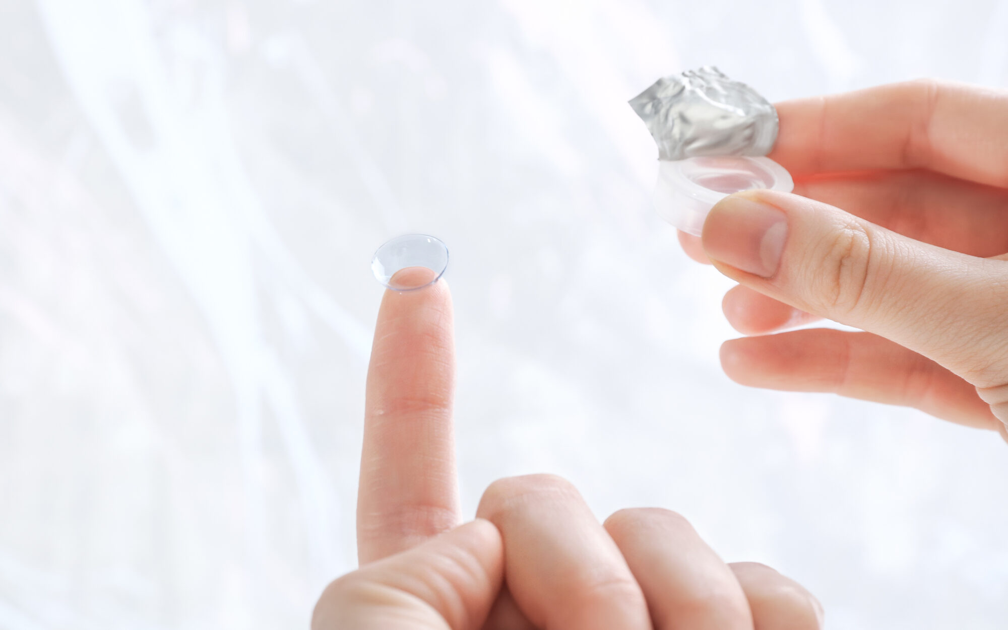 Gas permeable contact lenses being held by woman outside of photo edited