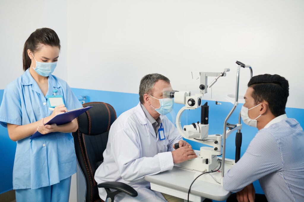 Man with face mask undergoes eye exam to determine if he is a candidate for a LASIK operation