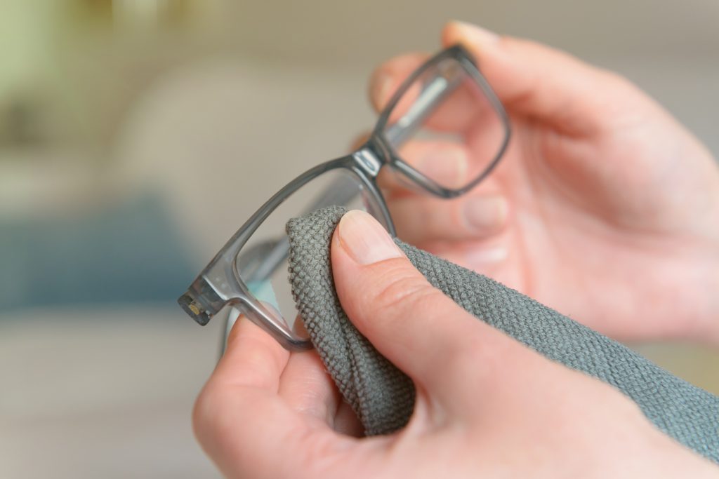 Woman cleaning eyeglasses with microfiber cloth