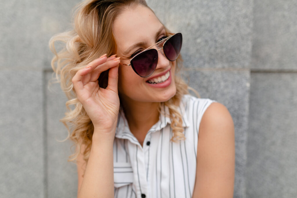 Young attractive stylish blonde woman walking in city street wearing sunglasses