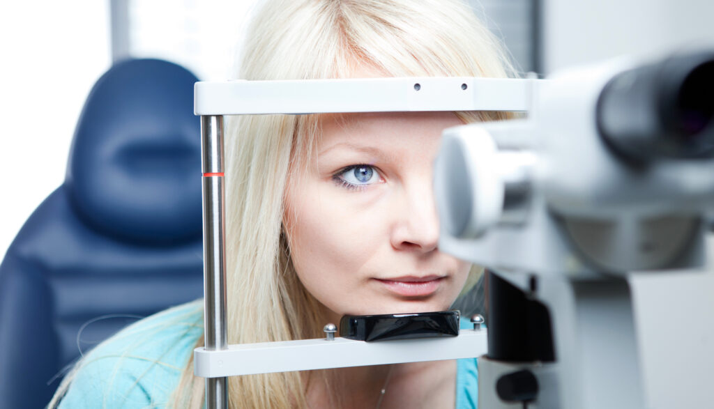 Young blonde woman getting her eye checked by optometrist