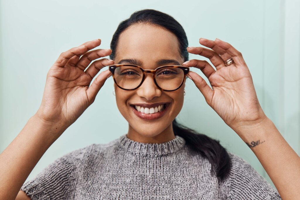 young woman smiling widely as she wears new pair of eyeglasses